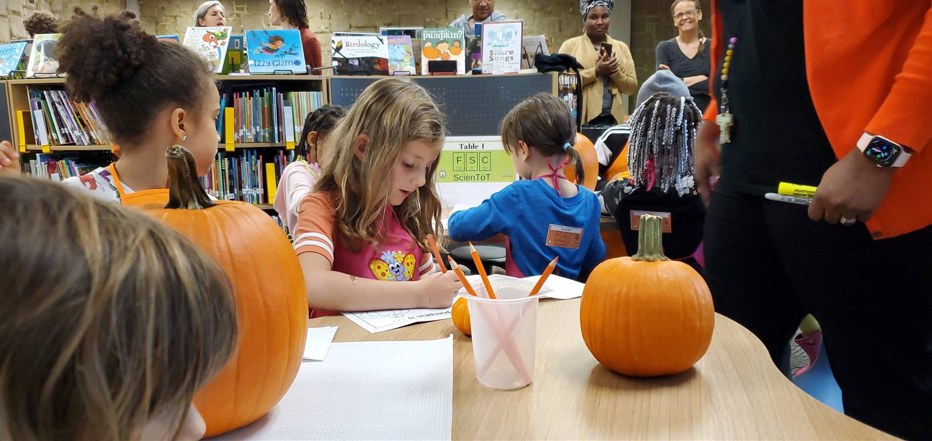 young children working at a table with pumpkins