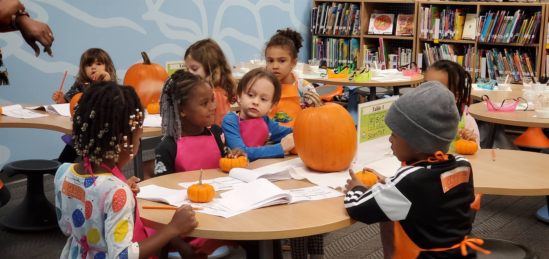 young children working at a table with pumpkins