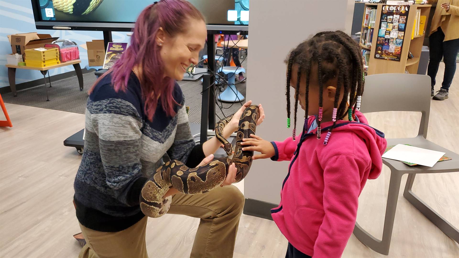 young girl petting a boa held by Dr. Kate