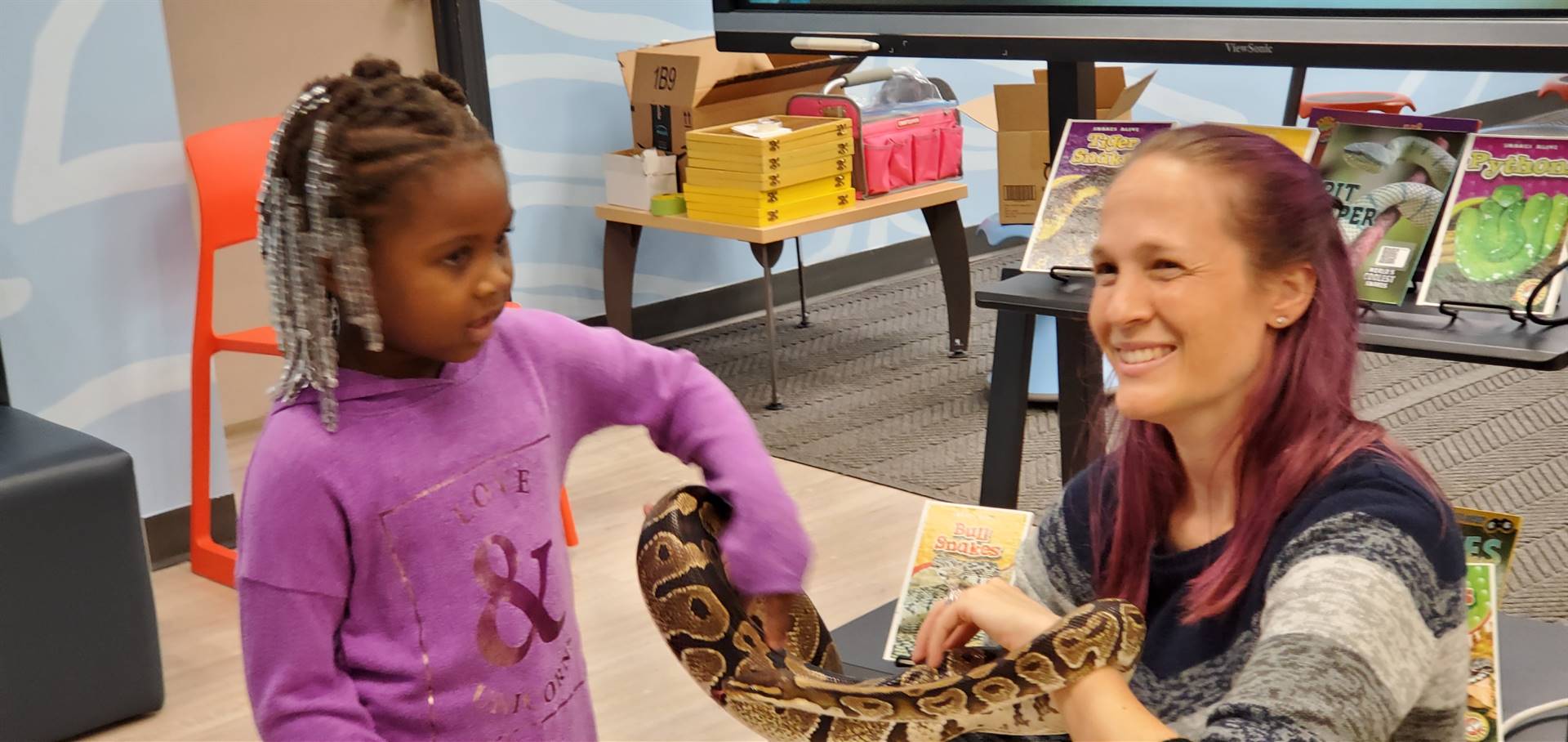 young girl petting a boa held by Dr. Kate